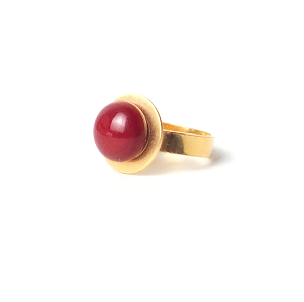 Red large button adjustable ring from the PIB collection by PLATÓNICA. Gold plated silver and glass. Minimalist jewelry. Contemporary jewelry. Author jewelry. Made in Granada, Andalusia, Spain. Jewelry workshop in the Albaicín. Crafts. Hand-made jewelry. Jewels made from Andalusia. Geometry. Modern and sophisticated style.