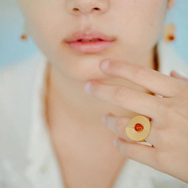 Orange open disc ring from the PIB collection by PLATÓNICA. Gold plated silver and glass. Minimalist jewelry. Contemporary jewelry. Author jewelry. Made in Granada, Andalusia, Spain. Jewelry workshop in the Albaicín. Crafts. Hand-made jewelry. Jewels made of Andalusia. Geometry. Modern and sophisticated style.