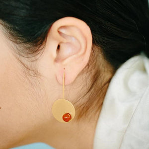 Orange long disc earrings from the PIB collection by PLATÓNICA. Gold plated silver and glass. Minimalist jewelry. Contemporary jewelry. Author jewelry. Made in Granada, Andalusia, Spain. Jewelry workshop in the Albaicín. Crafts. Hand-made jewelry. Jewels made from Andalusia. Geometry. Modern and sophisticated style.